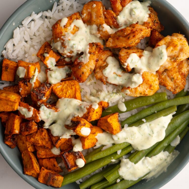 Chicken sweet potato bowls with a drizzle of green sauce on top.