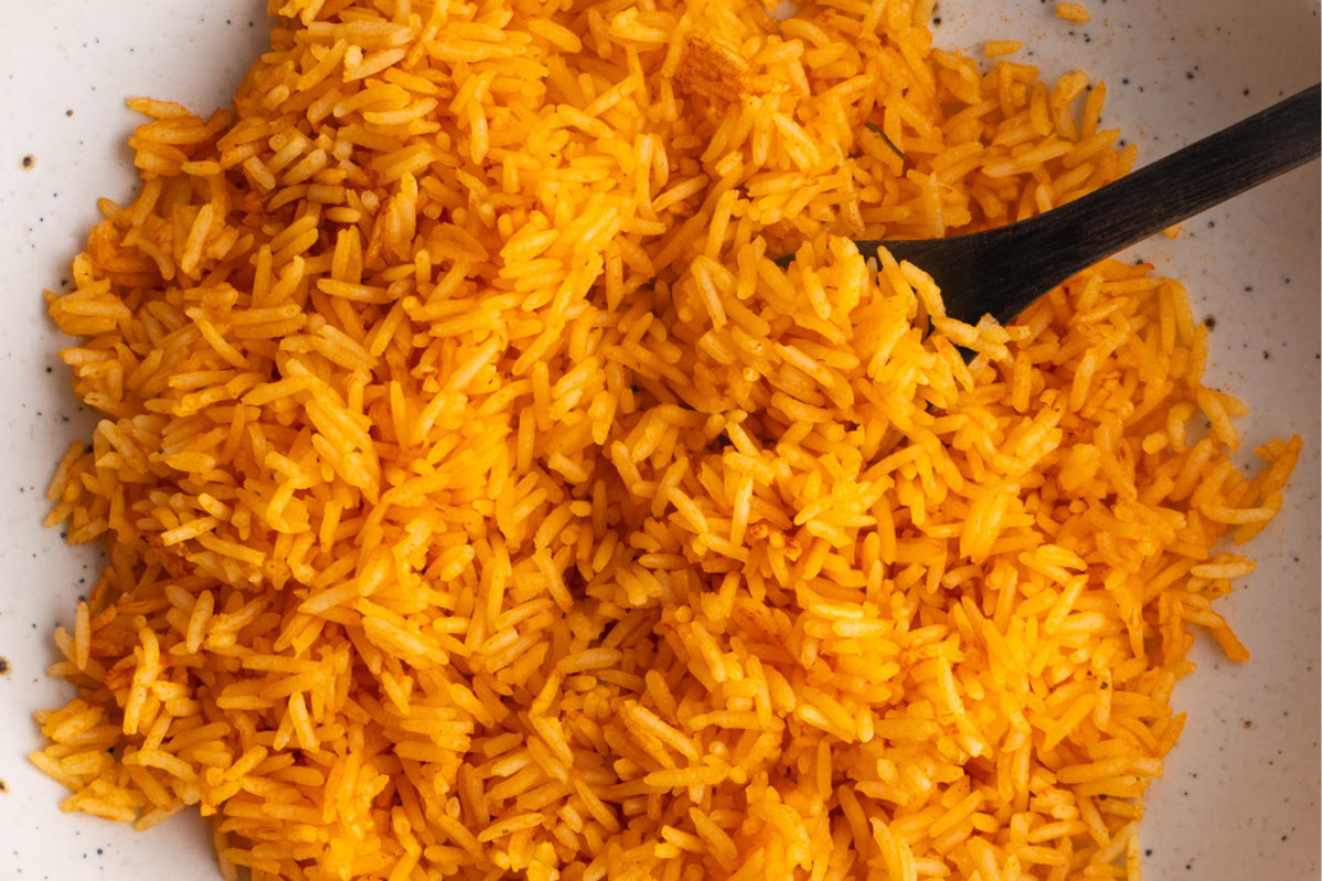 Close up of quick and easy Mexican rice in a bowl with a small spoon.