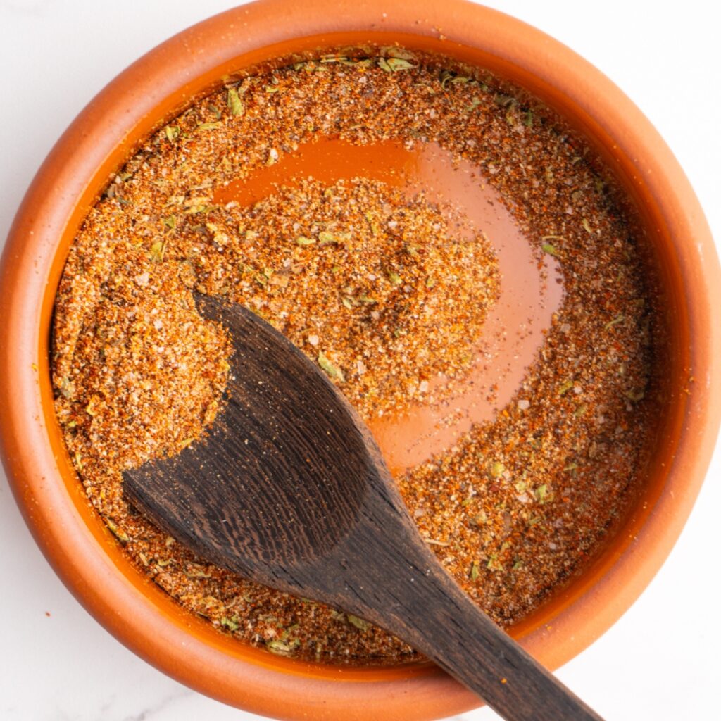 Close up of taco seasoning in a bowl with a small wooden spoon.