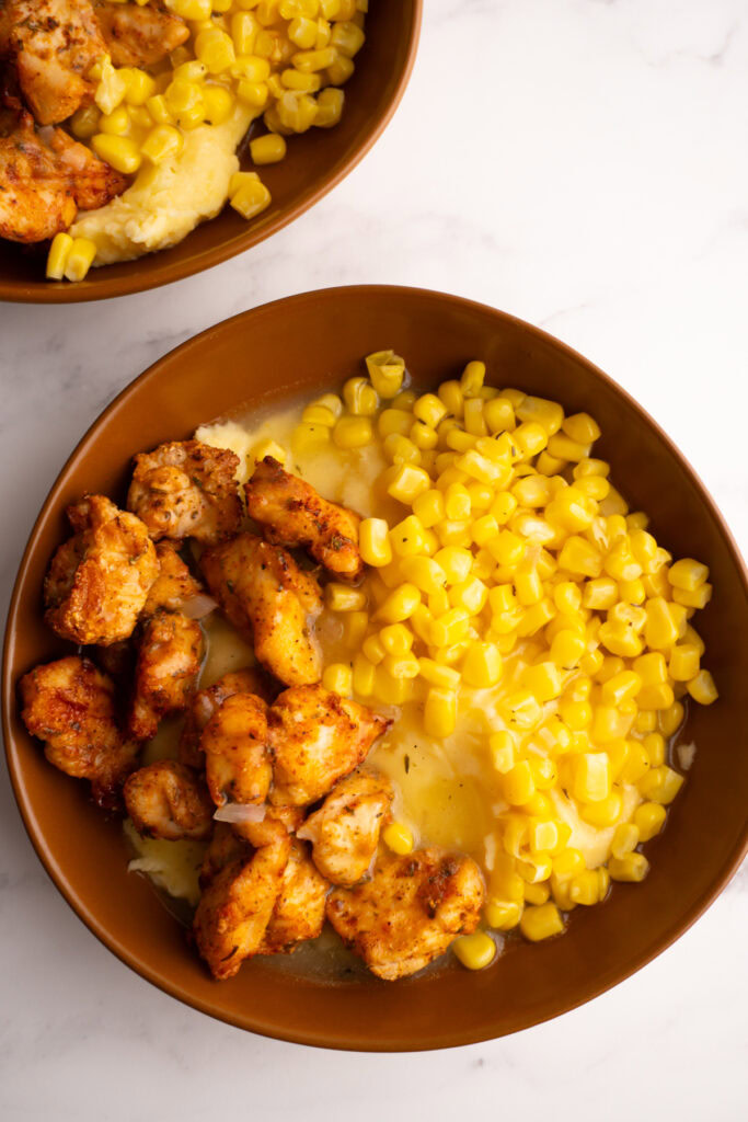 Overhead shot of a mashed potato bowl with chicken and corn in it.