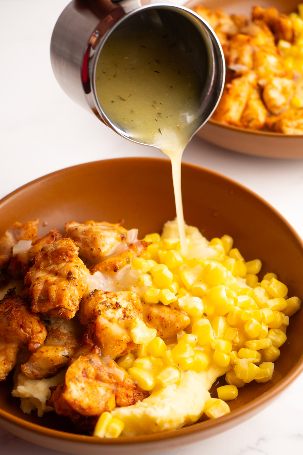 Pouring graving over the top of a mashed potato bowl.