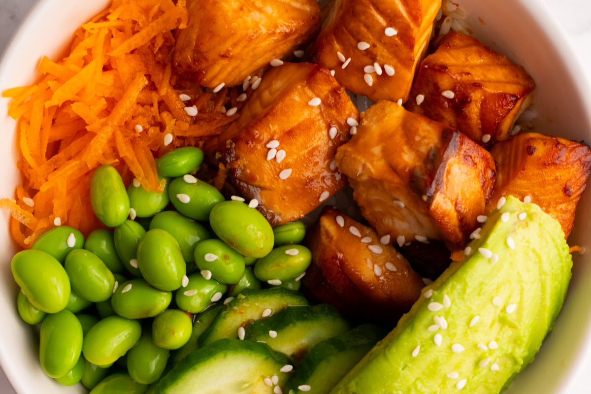 Close up of a cooked salmon poke bowl garnished with sesame seeds.