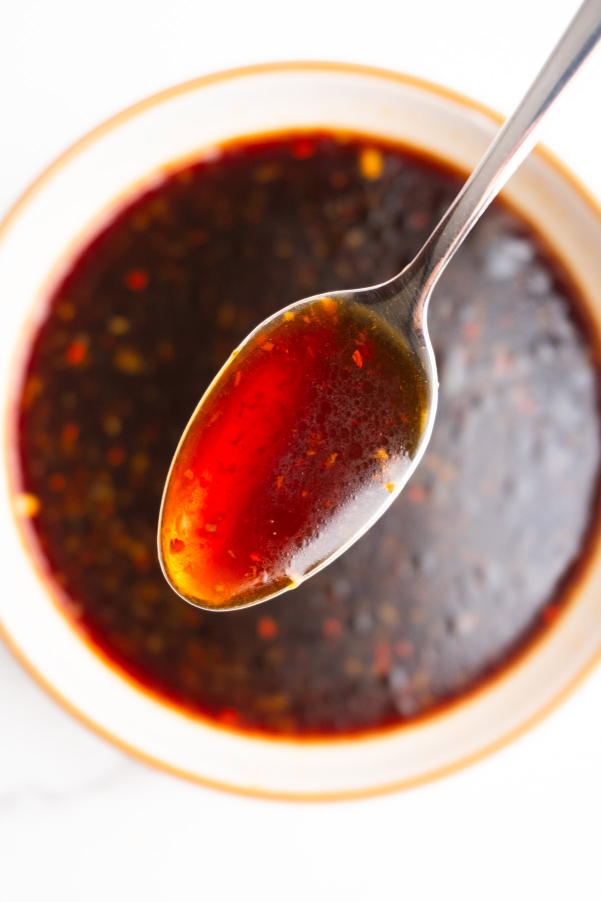 Spoon with poke bowl sauce hovering over the bowl.