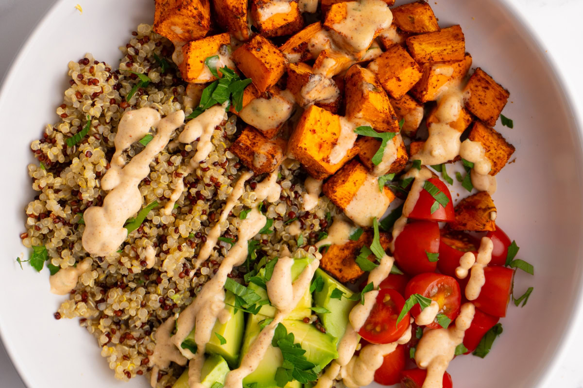 Close up of a sweet potato taco bowl drizzled with taco sauce on top.