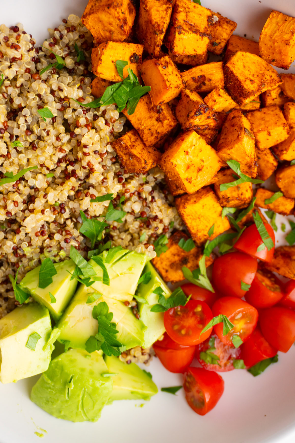 Close up of roasted sweet potatoes, quinoa, and veggies in a bowl.