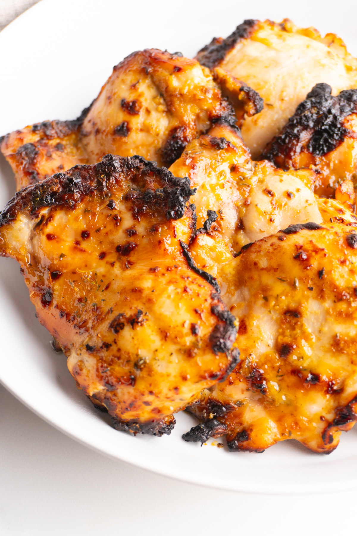 Air fryer honey mustard chicken thighs leaning on each other in a bowl.