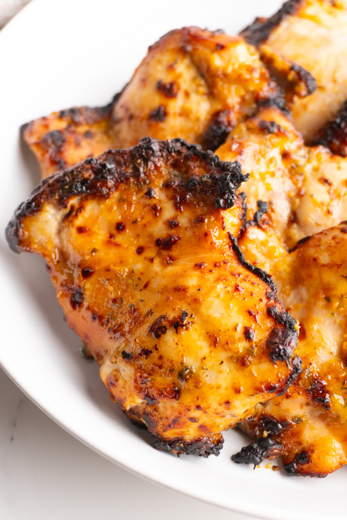 Close up of an air fryer honey mustard chicken thigh with caramelized edges.