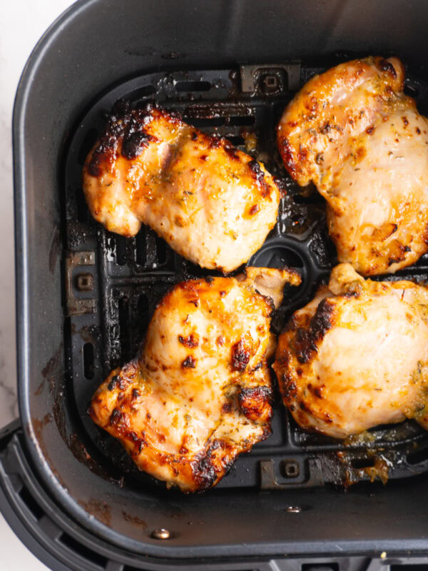 Air fryer honey mustard chicken thighs in the air fryer basket after cooking.