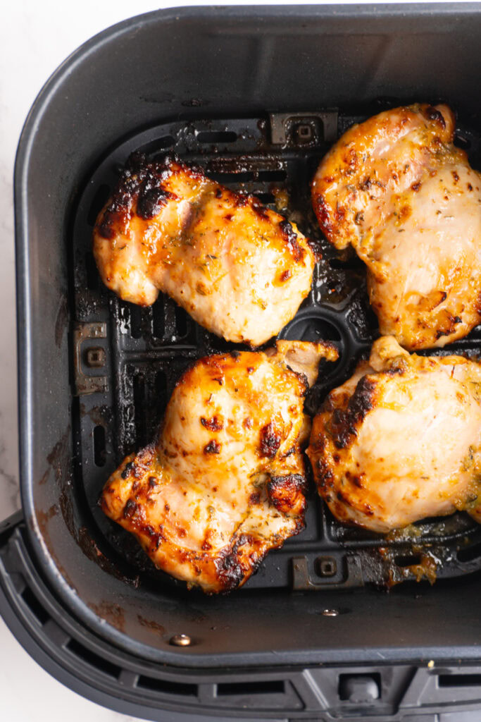 Air fryer honey mustard chicken thighs in the air fryer basket after cooking.
