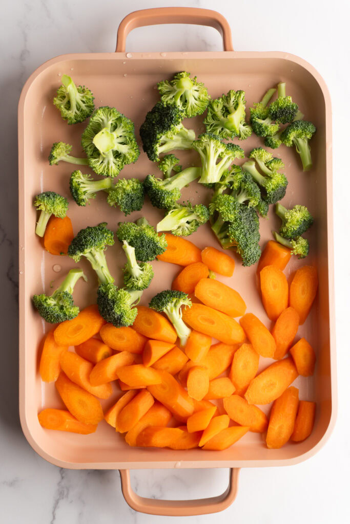 Broccoli and carrots on a sheet pan before being seasoned.
