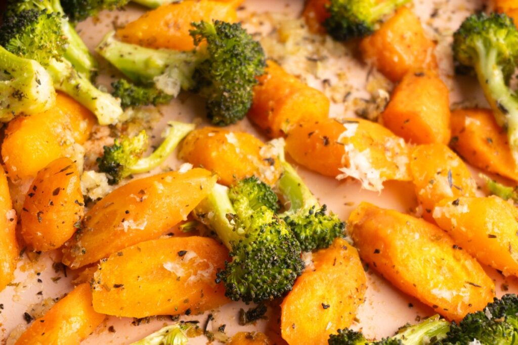Close up of roasted carrots and broccoli with parmesan cheese on top.