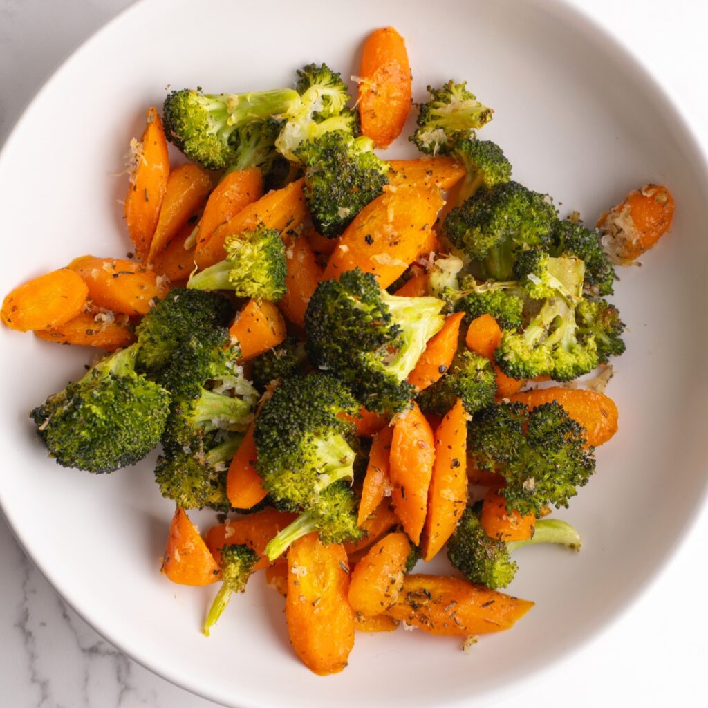 Overhead shot of roasted carrots and broccoli in a bowl.