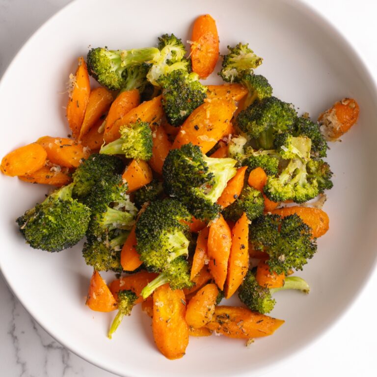 Overhead shot of roasted carrots and broccoli in a bowl.