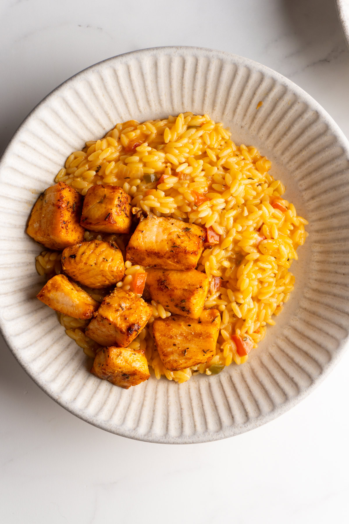 Overhead shot of salmon with cajun orzo in a bowl.
