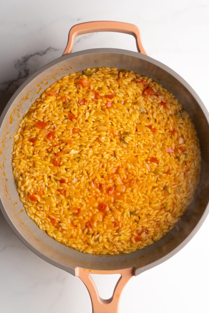 Cajun orzo in a skillet before stirring in the cream and cheese.