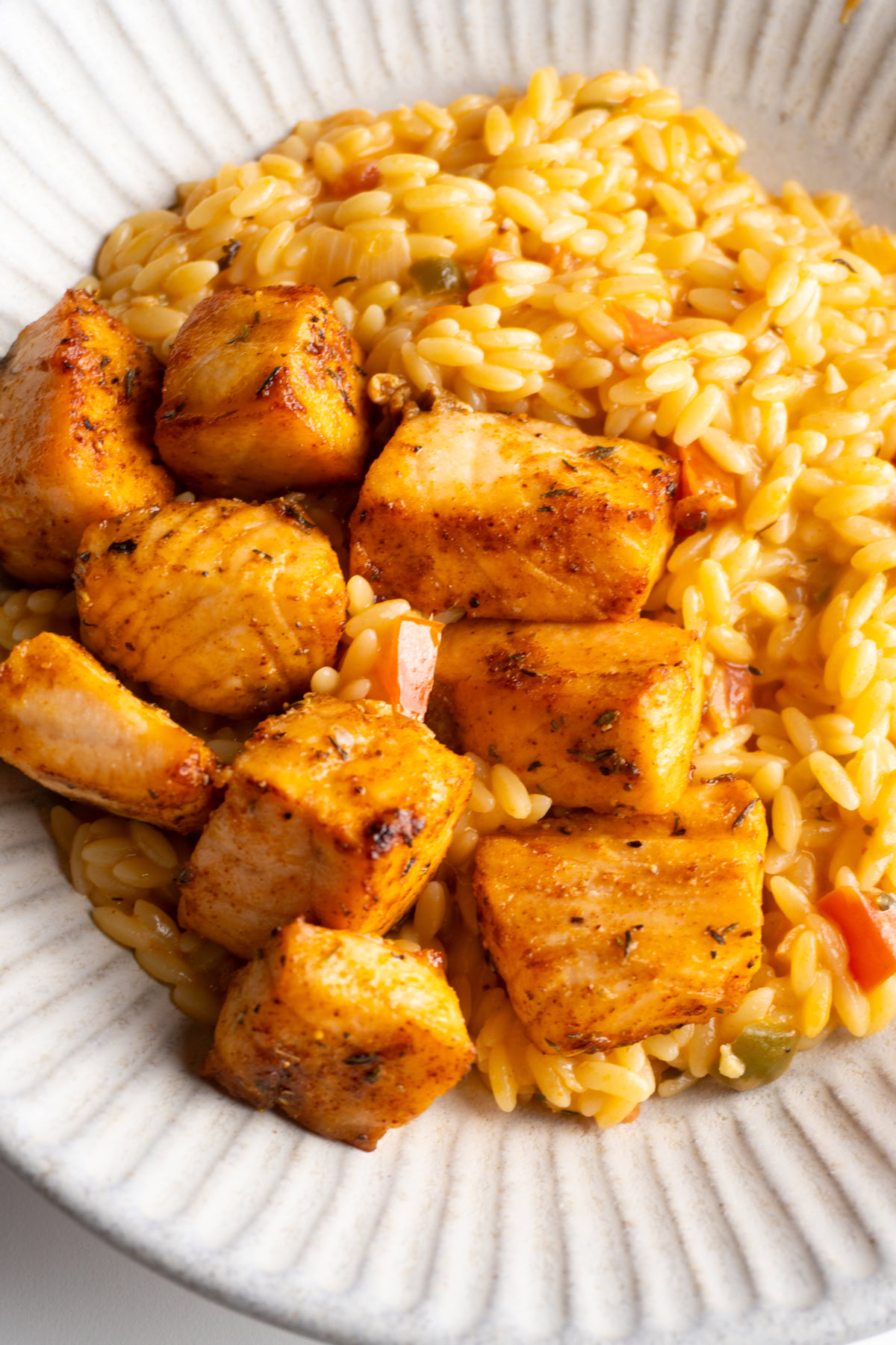 Cajun salmon bites served with cajun orzo in a bowl.