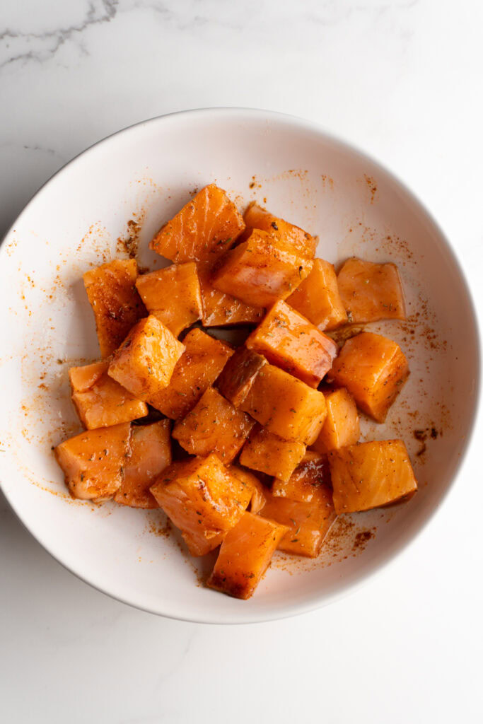 Salmon cubes mixed with olive oil and seasonings.