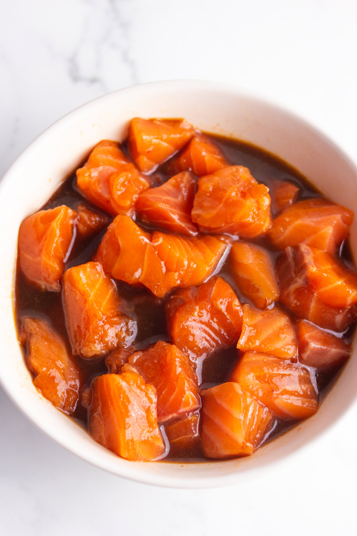 Diced fresh salmon in poke sauce in a bowl.