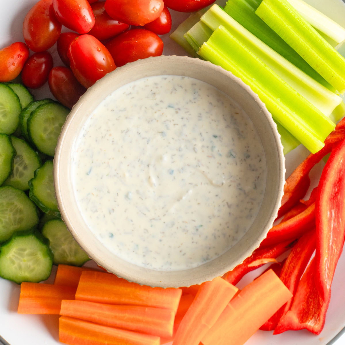 Small bowl of healthy ranch served with a platter of vegetables.
