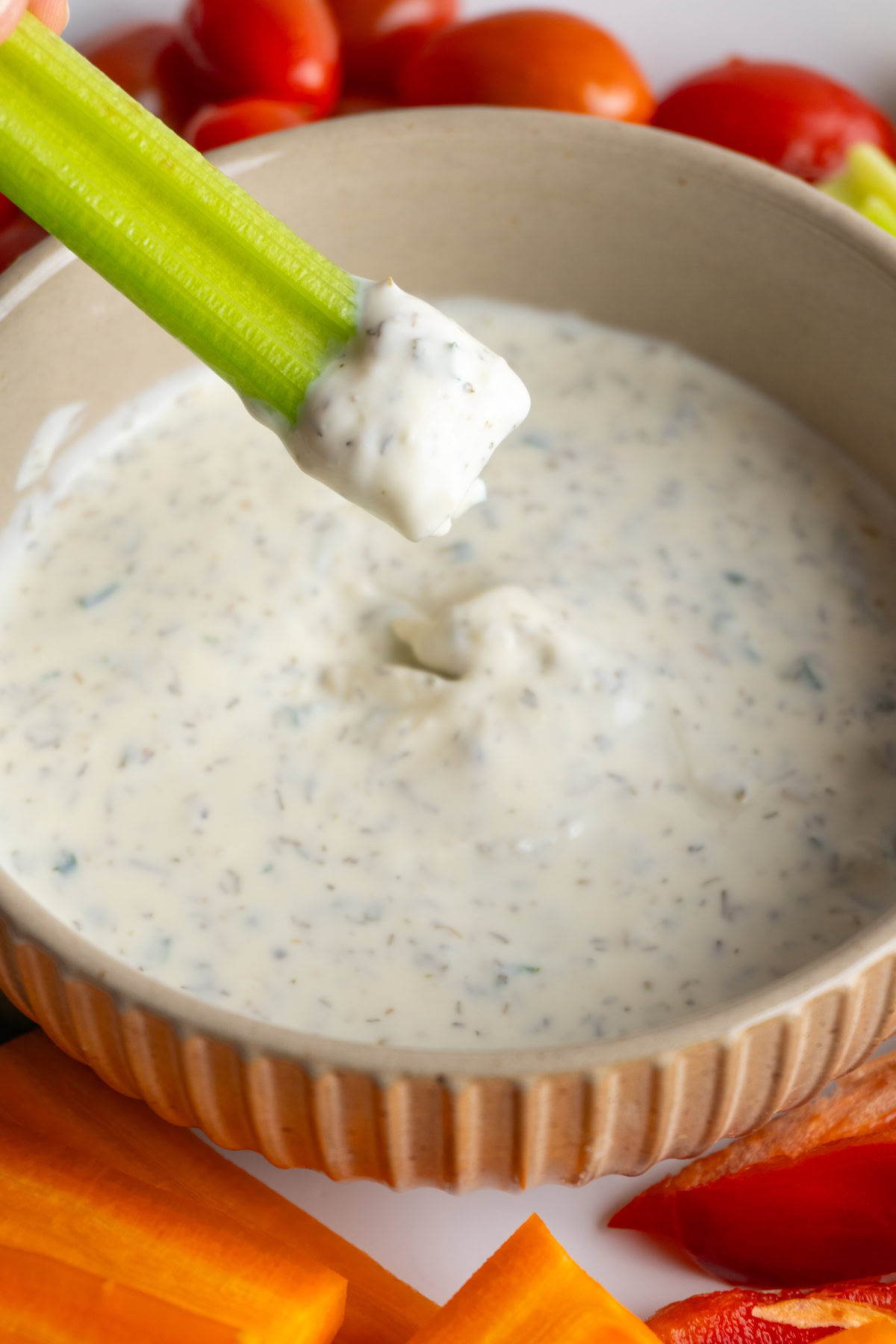 Celery being dipped into a small bowl of healthy ranch.