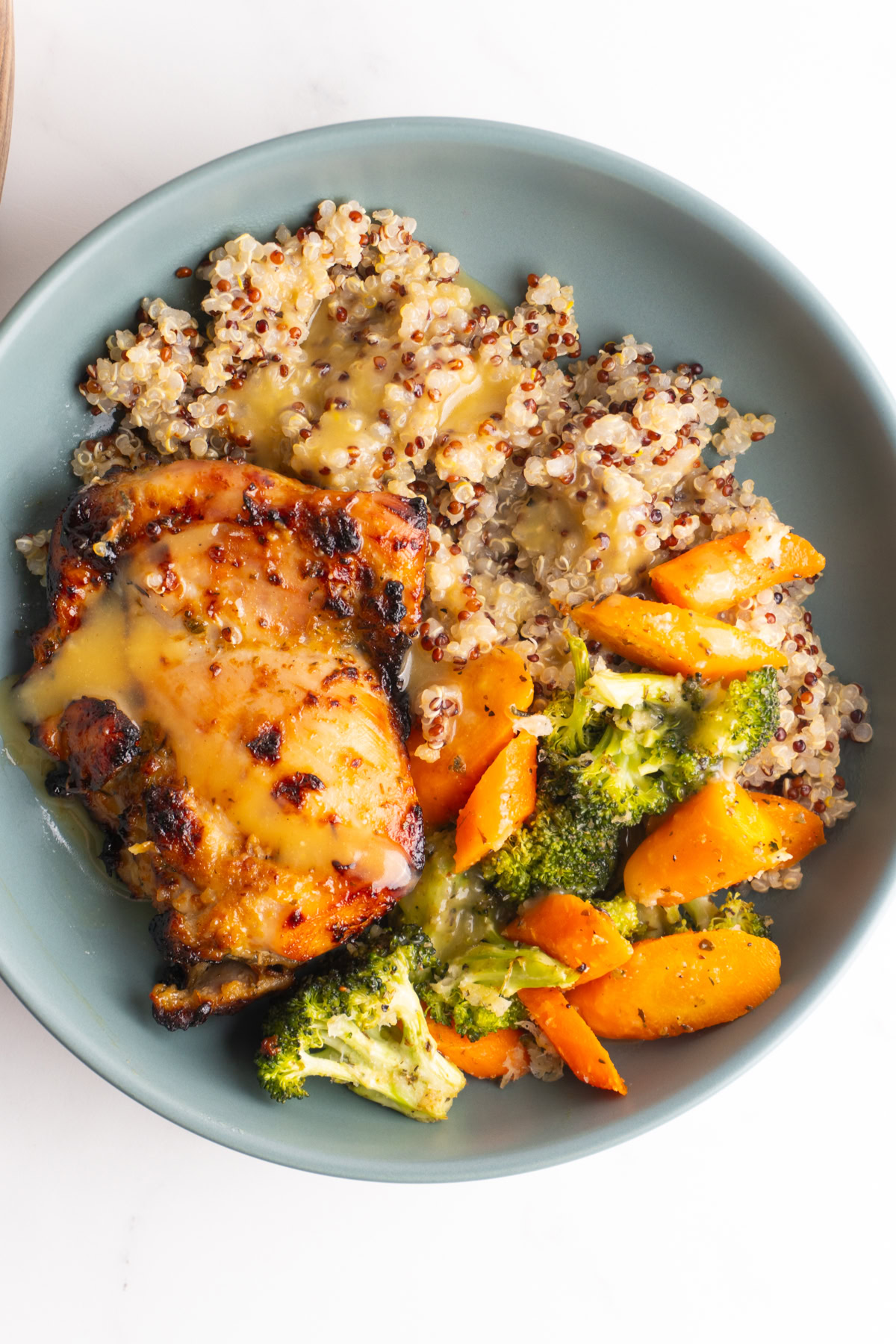 Honey mustard chicken bowl with quinoa topped with honey mustard vinaigrette.