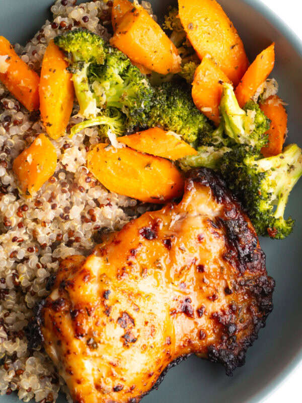 Close up of honey mustard chicken with quinoa and roasted veggies in a bowl.