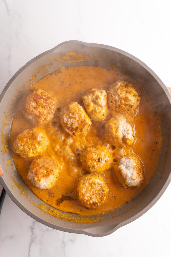 Chicken meatballs added back to the marry me sauce in a skillet.