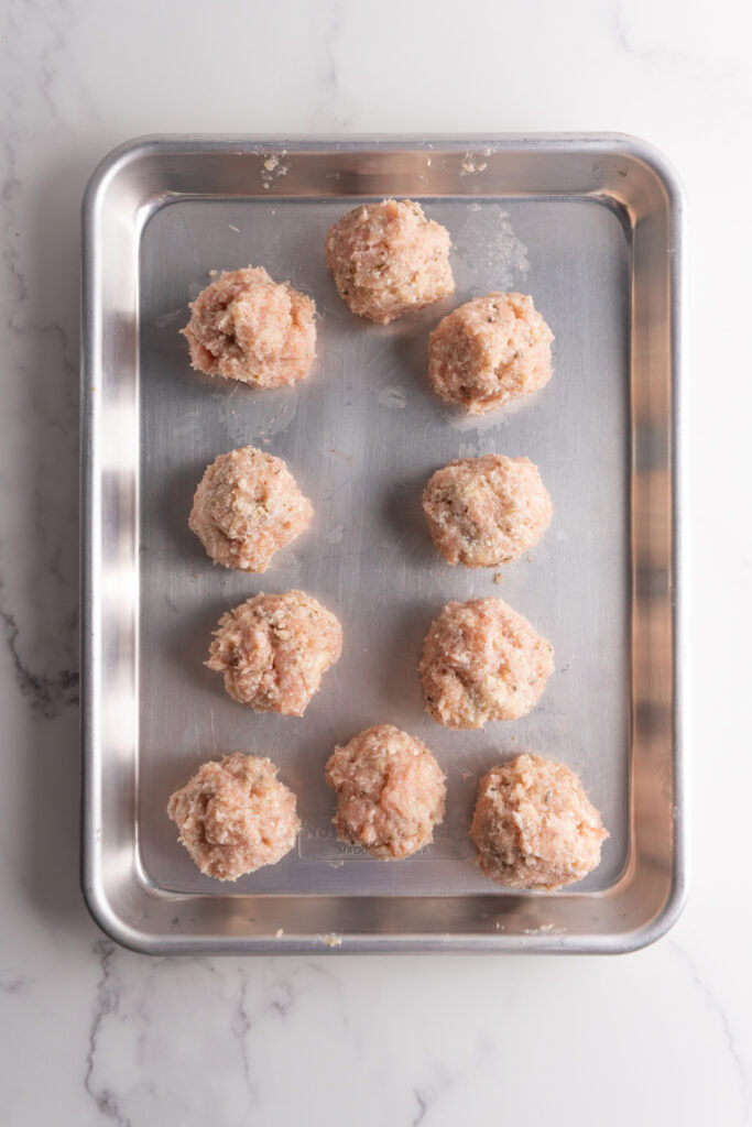 Marry me chicken meatballs rolled into balls and placed on a sheet pan.
