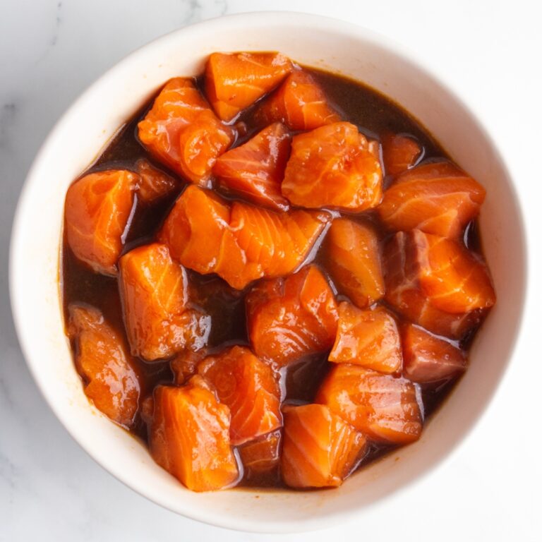 Diced fresh salmon in a bowl with poke bowl sauce.