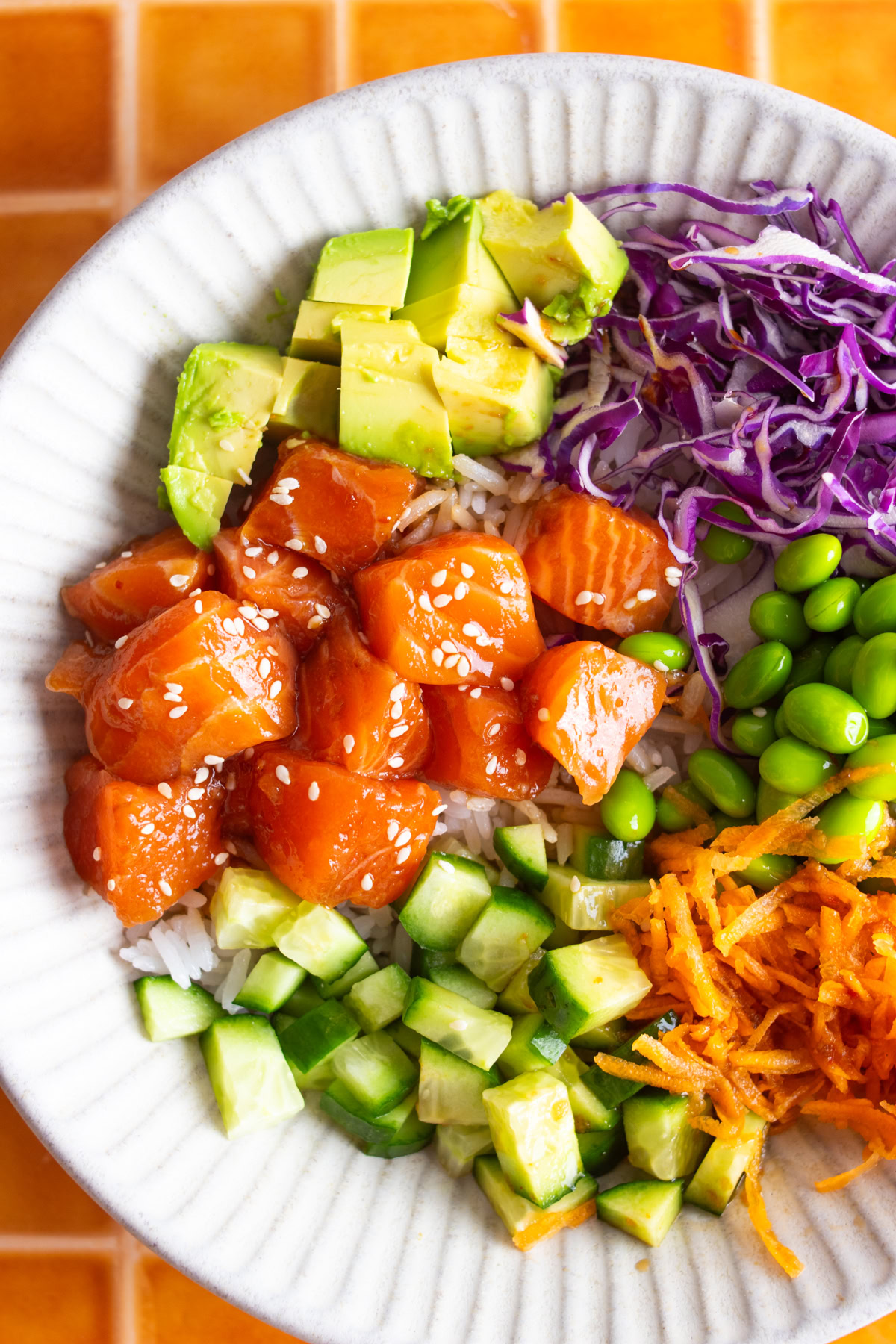 Fresh salmon poke in a bowl with rice and toppings.