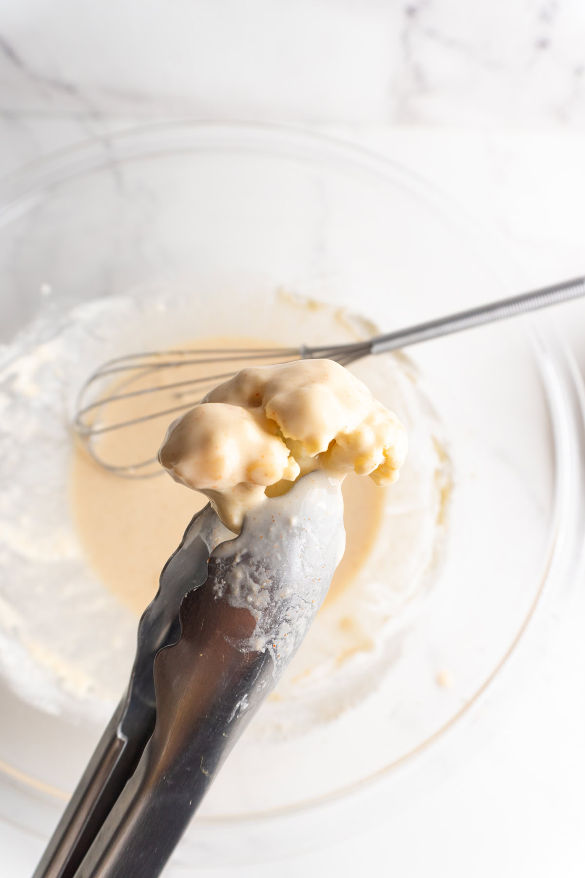 Cauliflower dipped in a flour batter in a bowl.