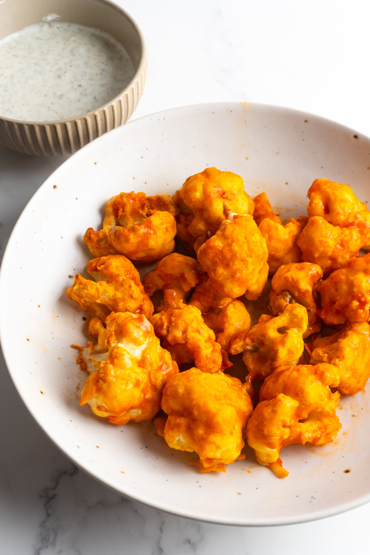 Air fryer buffalo cauliflower next to a small bowl of ranch.