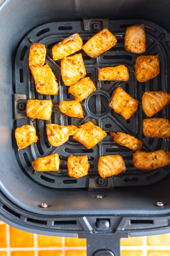 Salmon bites in the basket of an air fryer.