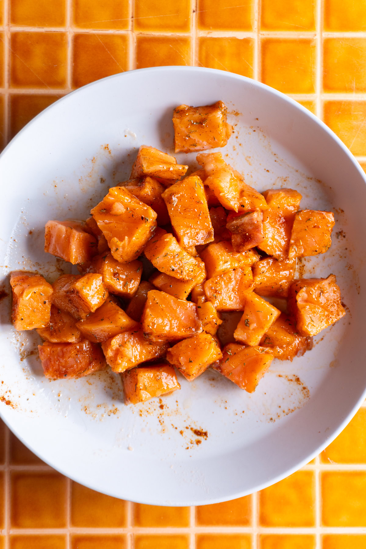 Diced salmon mixed together with spices in a bowl.
