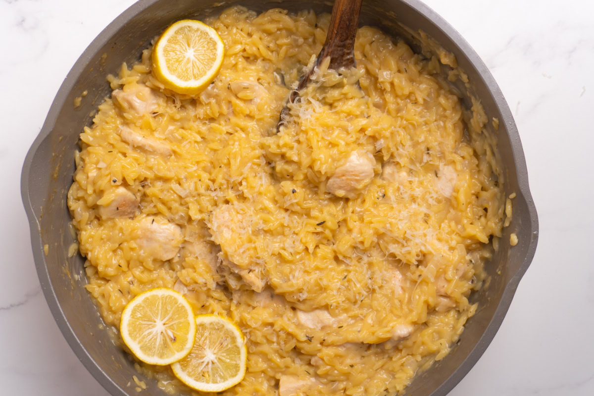 One pan lemon chicken orzo topped with parmesan in a skillet.