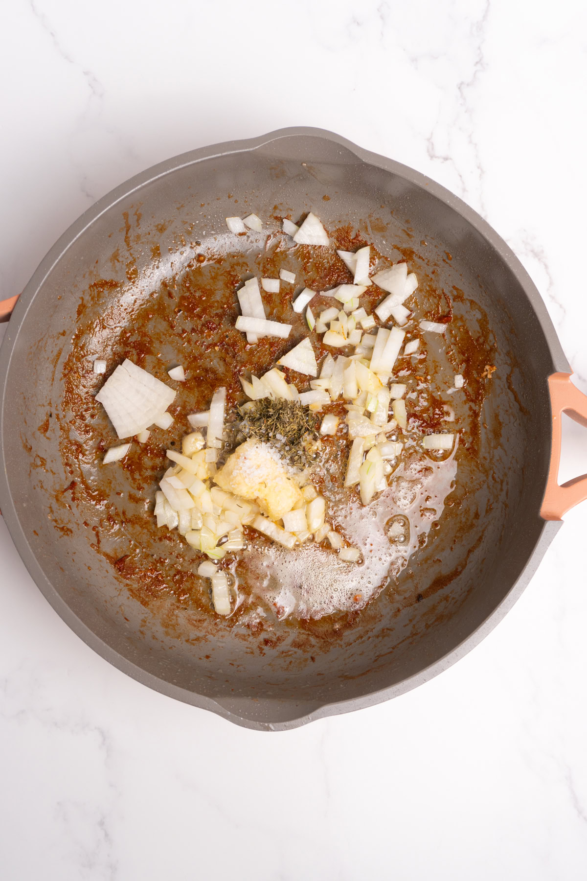 Onion, garlic and spices added to the same skillet as the chicken.
