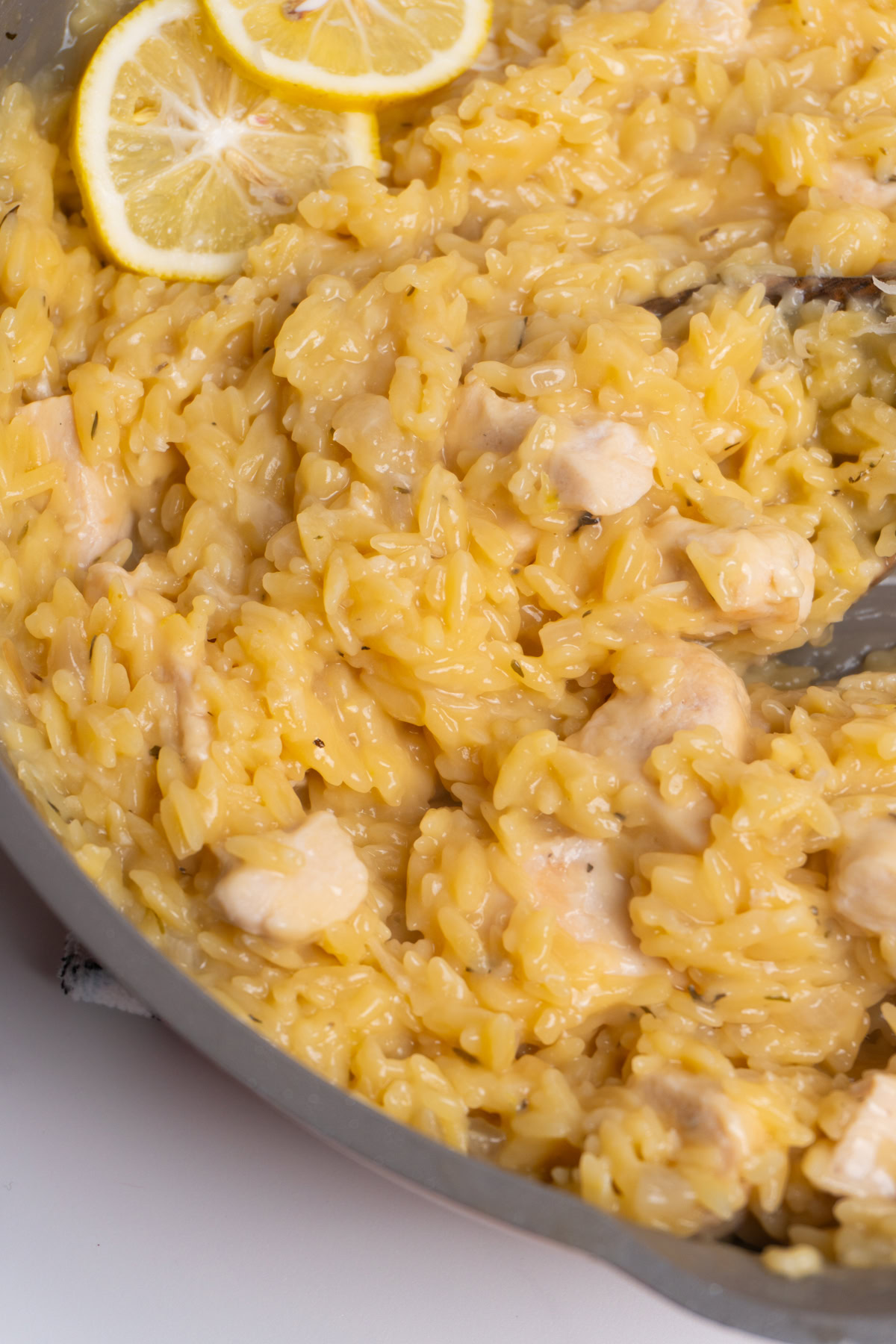 Close up of lemon orzo chicken in a skillet with a spoon.