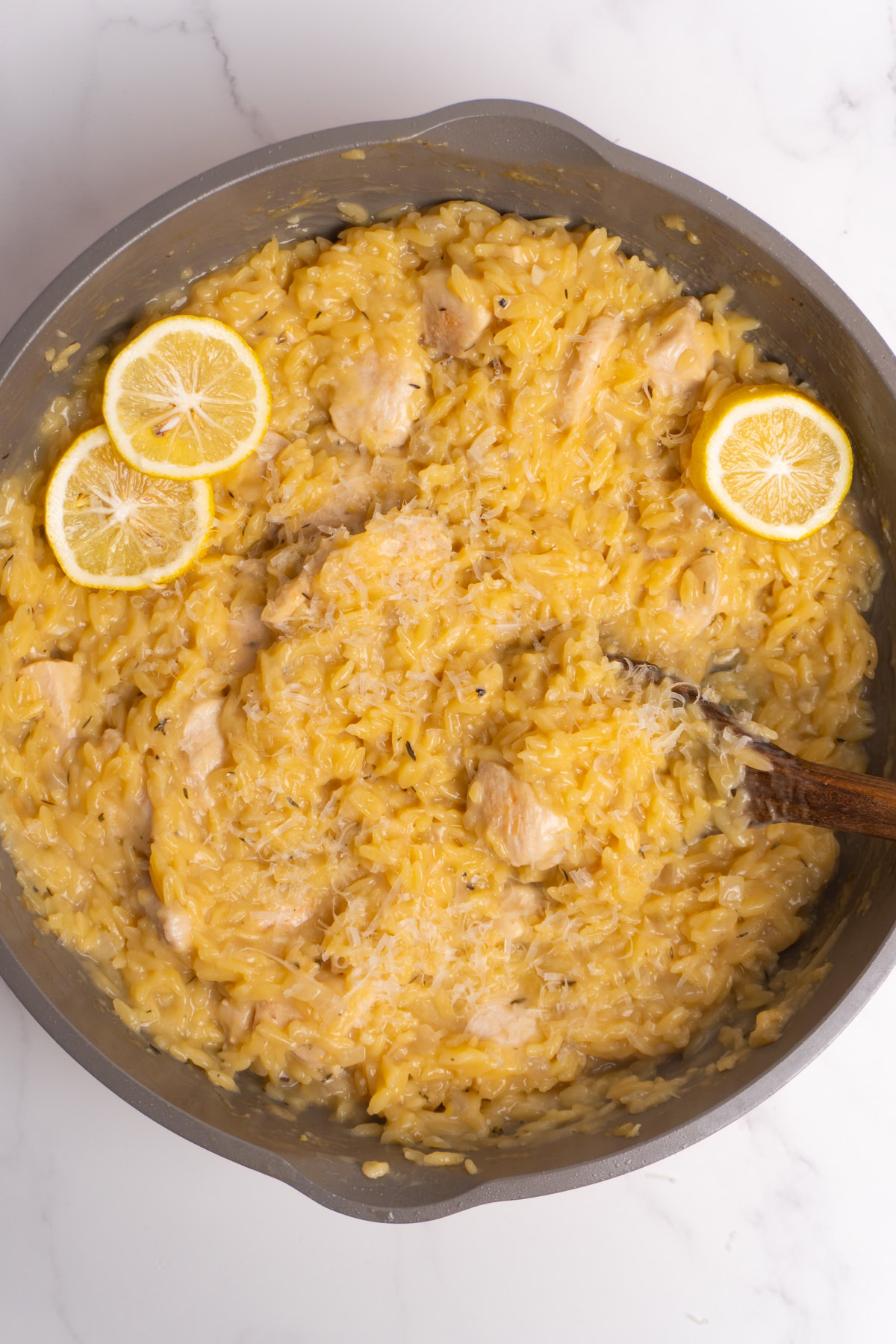 Finished lemon chicken orzo skillet with a spoon.