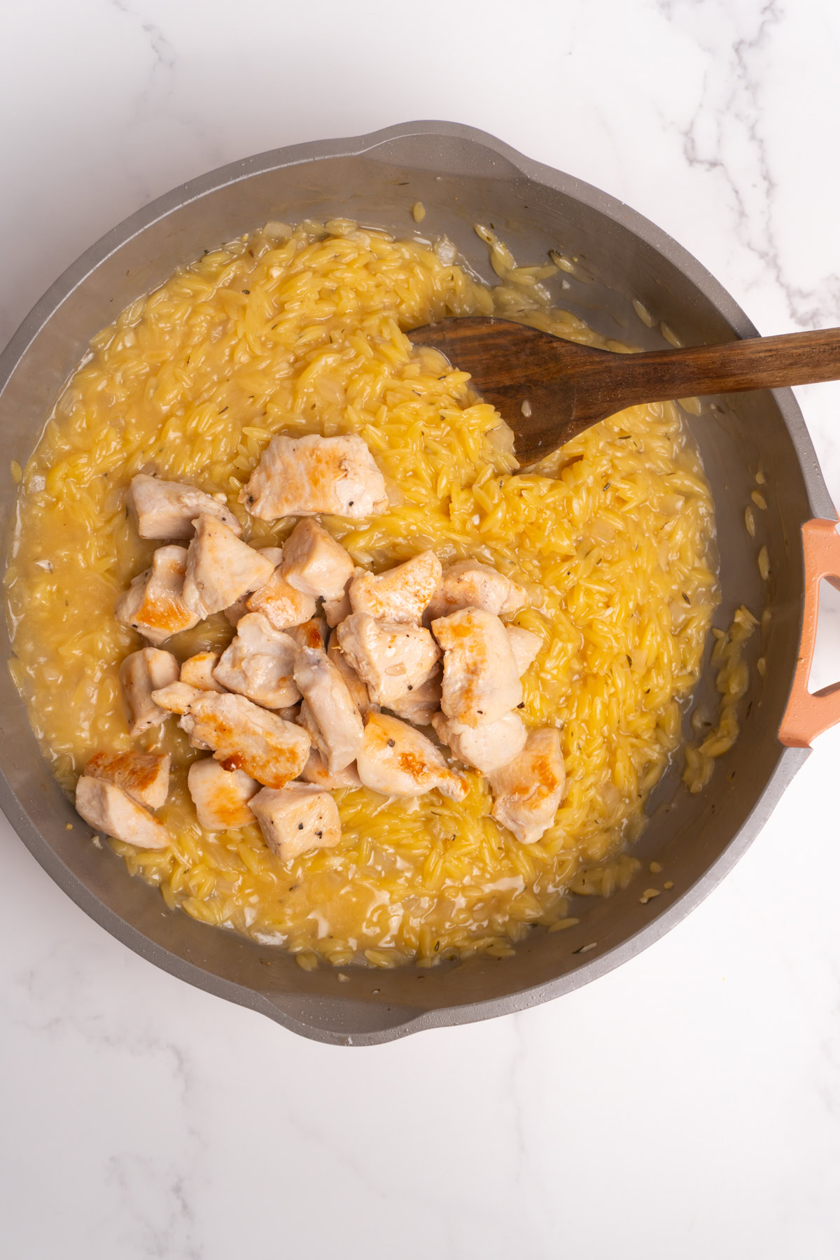 Chicken added back to the lemon orzo in a skillet.