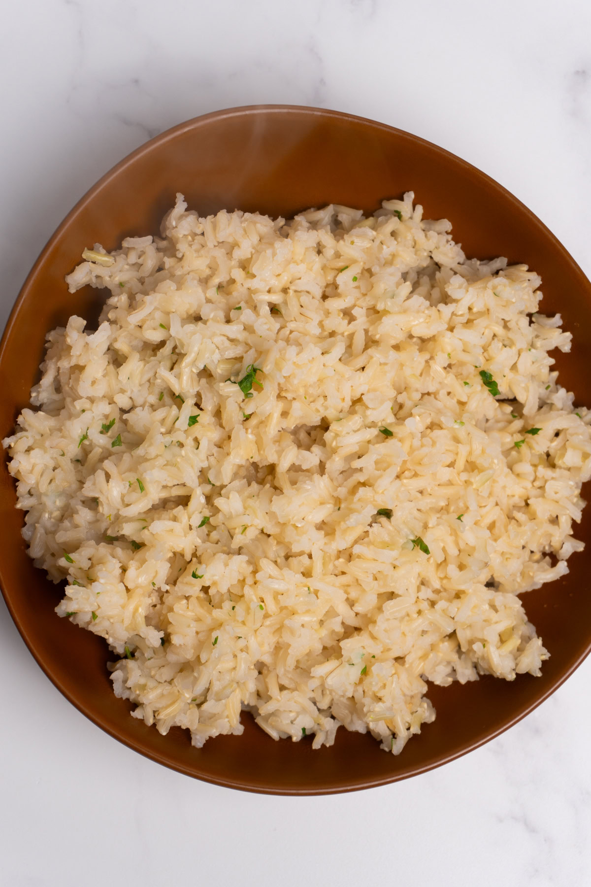 Finished cilantro lime brown rice served in a brown bowl.