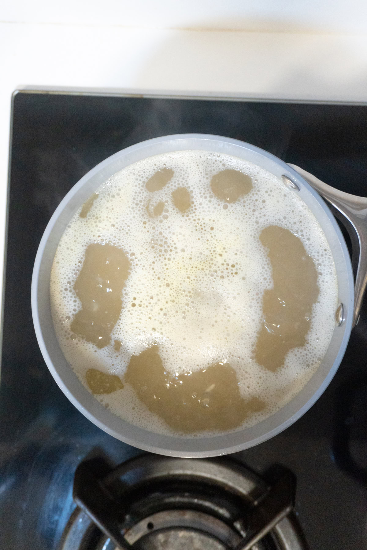 Brown rice in broth simmering in a saucepan.